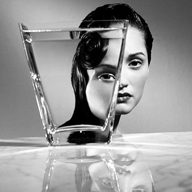 a woman's face is reflected in a glass vase