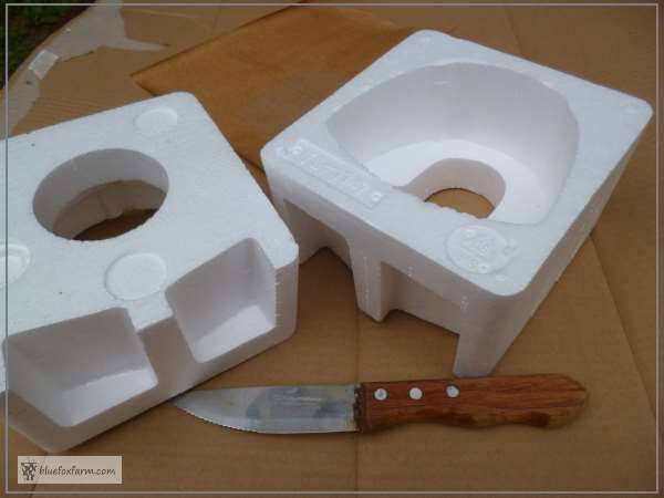 two white plastic containers and a knife on a cardboard box