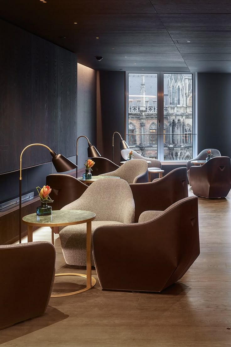 an empty room with chairs and tables in front of a large window that looks out onto the city