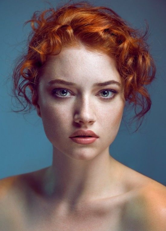 a woman with red hair and blue eyes is looking at the camera while posing for a portrait