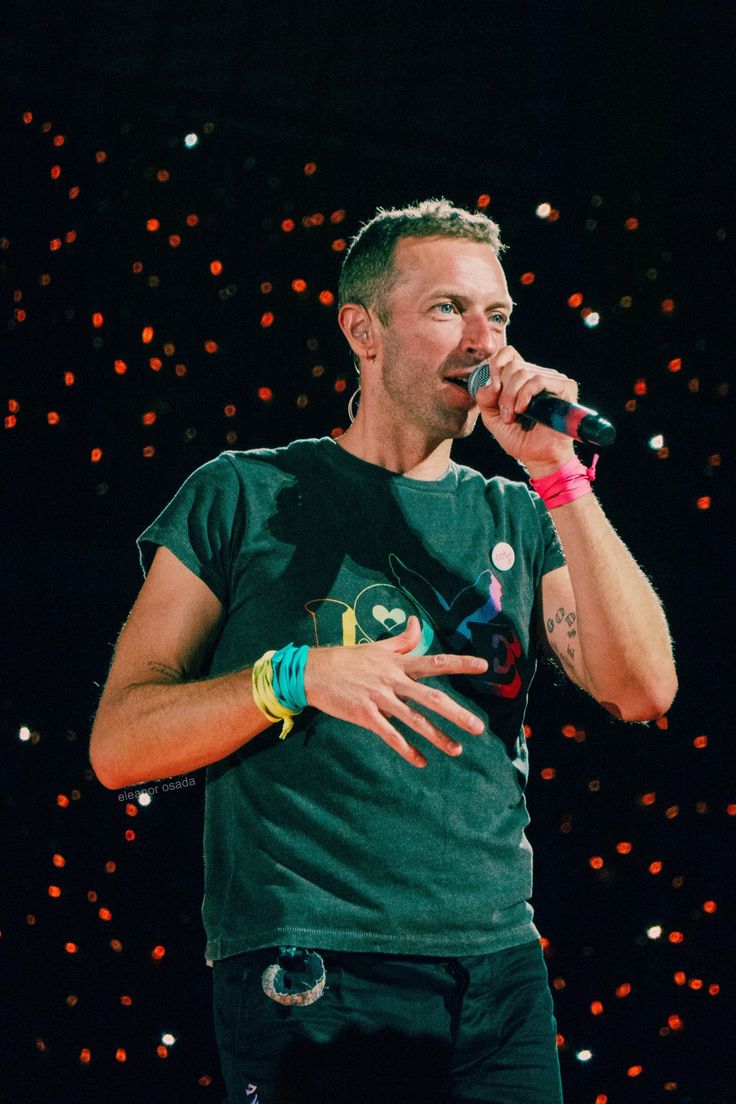 a man standing on top of a stage holding a microphone in his hand and singing