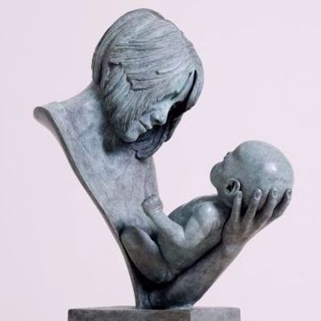 a statue of a woman holding a baby in her arms on top of a wooden block