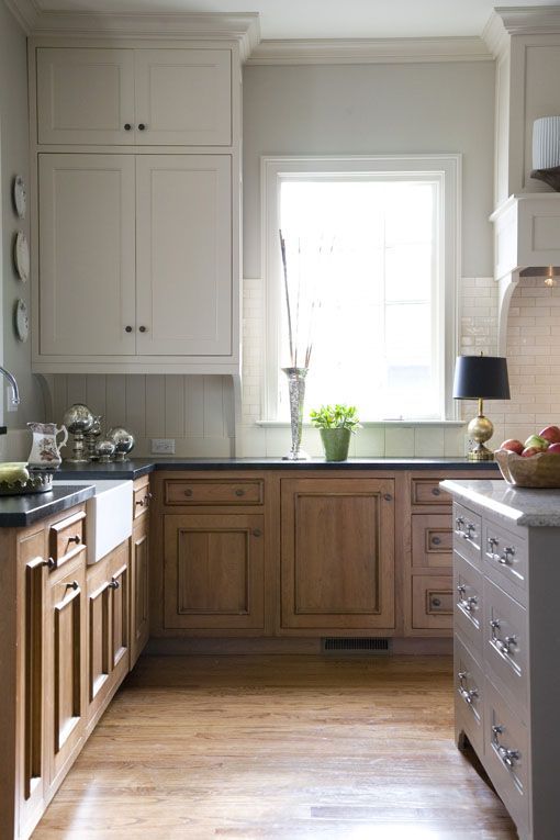 a kitchen with white cabinets and wood floors, an island countertop and sink area