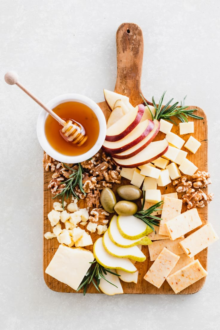 an apple and cheese platter with honey, walnuts, apples, pine nuts