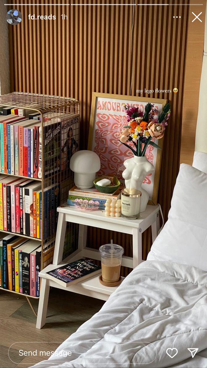 a bed with white sheets and pillows next to a book shelf filled with books on top of it