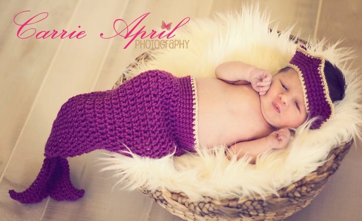 a baby is laying in a basket wearing a knitted hat and diaper with white fur