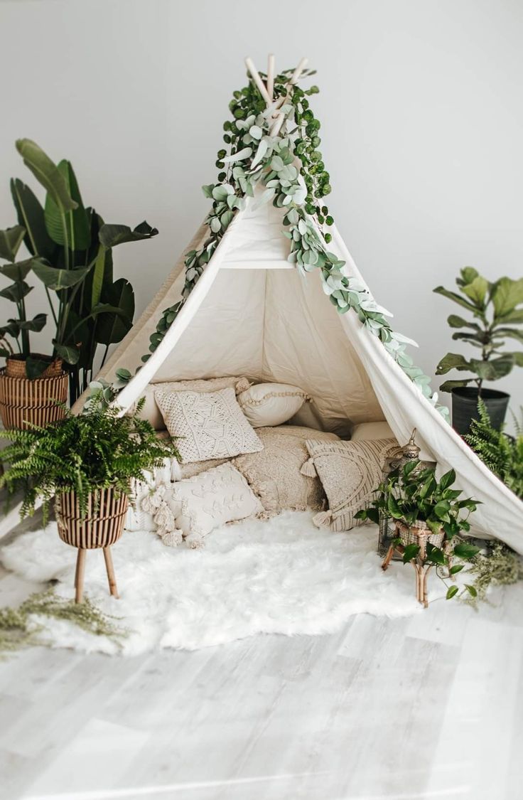 a teepee tent with plants and pillows on the floor