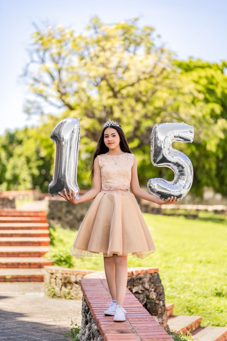 a young woman holding two silver balloons in front of her face and the number five