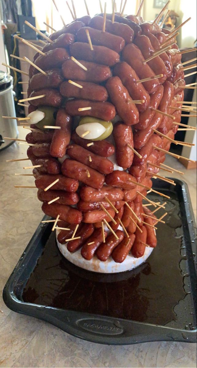 a pile of hotdogs sitting on top of a pan covered in toothpicks