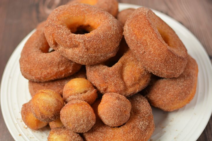 a pile of sugared doughnuts sitting on top of a white plate