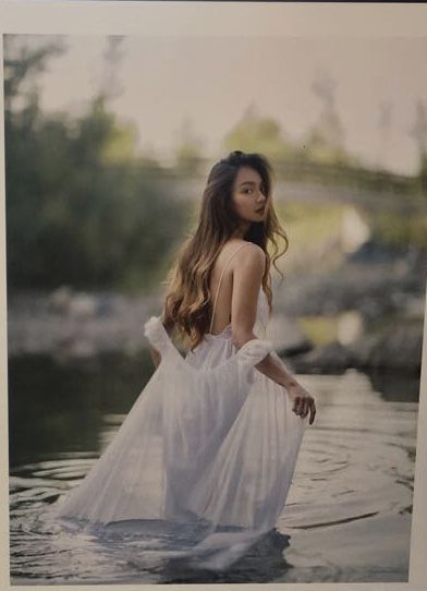 a woman standing in the water wearing a white dress