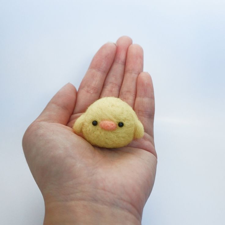 a hand holding a tiny yellow bird in it's palm