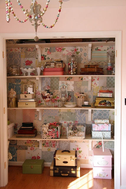 an open bookcase with many items on it and a chandelier hanging from the ceiling