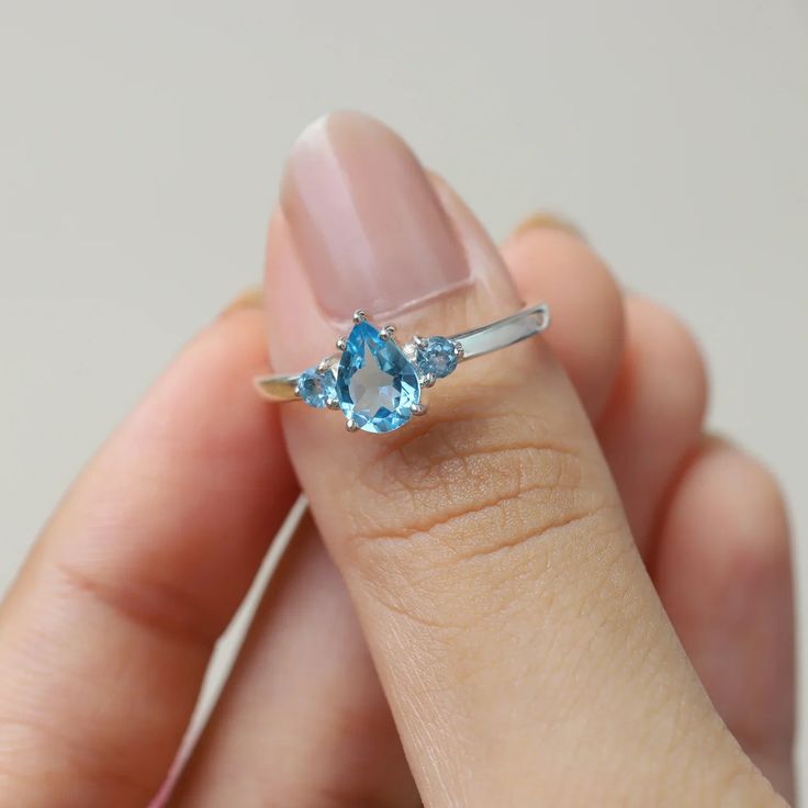 A classic cut, the pear-shaped Sienna ring with a side Swiss Blue Topaz is the ultimate ring to gift a loved one. It is a timeless piece that can always be paired with other nesting bands to elevate your look.  A ring that will never disappoint, and makes the perfect pre-engagement ring or promise ring for a friend. De Pear-shaped Topaz Promise Ring, Fine Jewelry Pear-shaped Topaz Ring, Fine Jewelry Blue Topaz Teardrop Rings, Fine Jewelry Pear-shaped Topaz Ring For Anniversary, Pear-shaped Topaz Ring For Anniversary, Fine Jewelry, Pear-shaped Topaz Promise Ring With Prong Setting, Pear-shaped Topaz Promise Ring With Accent Stones, Teardrop Topaz Ring With Accent Stones For Anniversary, Pear-shaped Topaz Ring For Anniversary