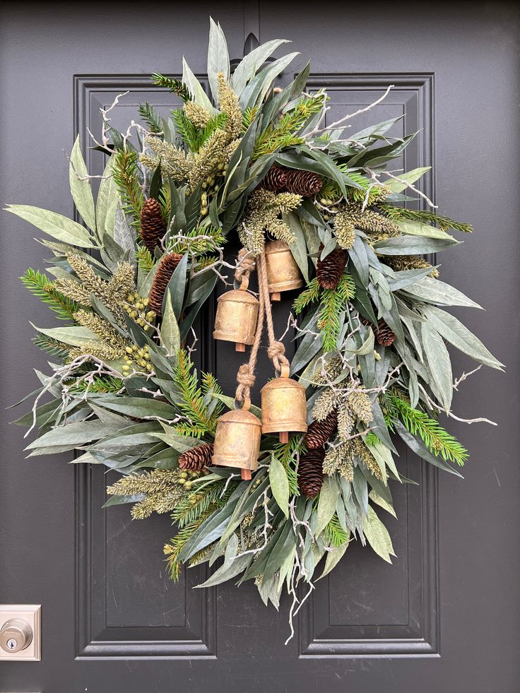 a wreath with bells and greenery on the front door