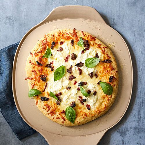 a pizza on a plate with basil leaves and cheese