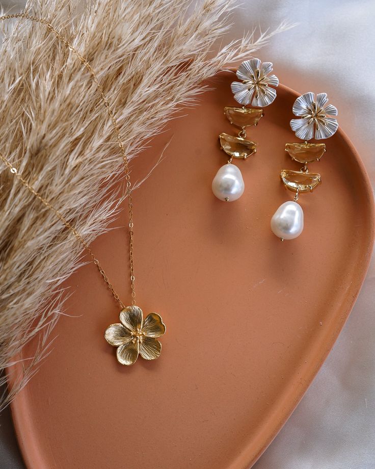 Make a beautiful statement with these one-of-a-kind Bloom Pearl Drop Earrings! Their elegance and stunning design will add the perfect touch of elegance to any look. Can be worn for date night or to your wedding! EARRINGS FEATURE Material: 18K gold plated brass, glass and shell pearls Size: 20x19mm Color: Gold Chic Flower Shaped Jewelry With Matching Earrings, Chic Flower-shaped Jewelry With Matching Earrings, Chic Flower-shaped Matching Earrings Jewelry, Chic Flower-shaped Matching Earrings, Feminine Gold Plated Earrings For Gift, Gold-plated Bridal Earrings For Party, Gold Plated Bridal Earrings For Party, Elegant Gold Flower Jewelry, Elegant Flower-shaped Gold Jewelry