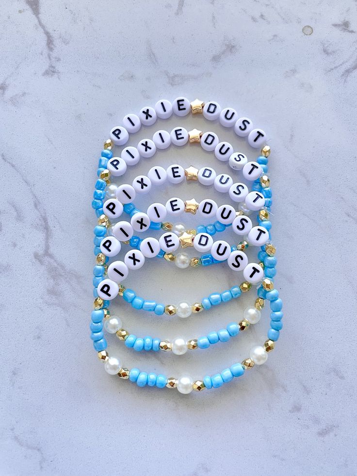 the beaded bracelets are made with white, blue and gold beads on a marble surface