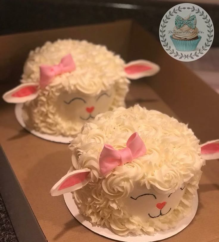 two cupcakes in the shape of sheep with pink bows