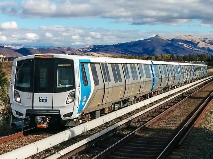 a train traveling down tracks next to mountains