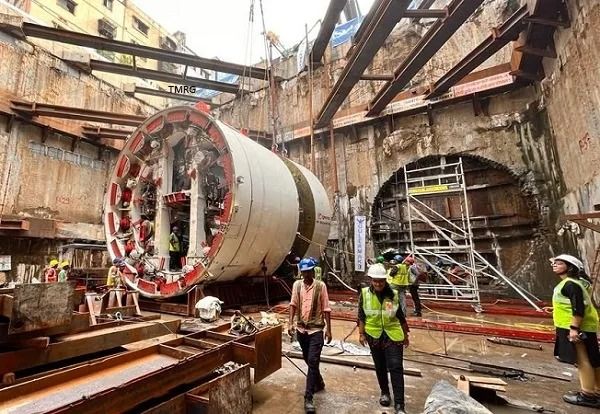 three men in safety vests are standing next to a large metal object that is being worked on