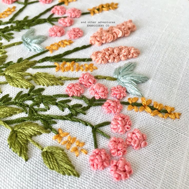 a close up of flowers on a white cloth with green and pink trimmings