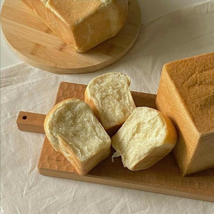 slices of bread sitting on top of a cutting board next to a loaf of bread