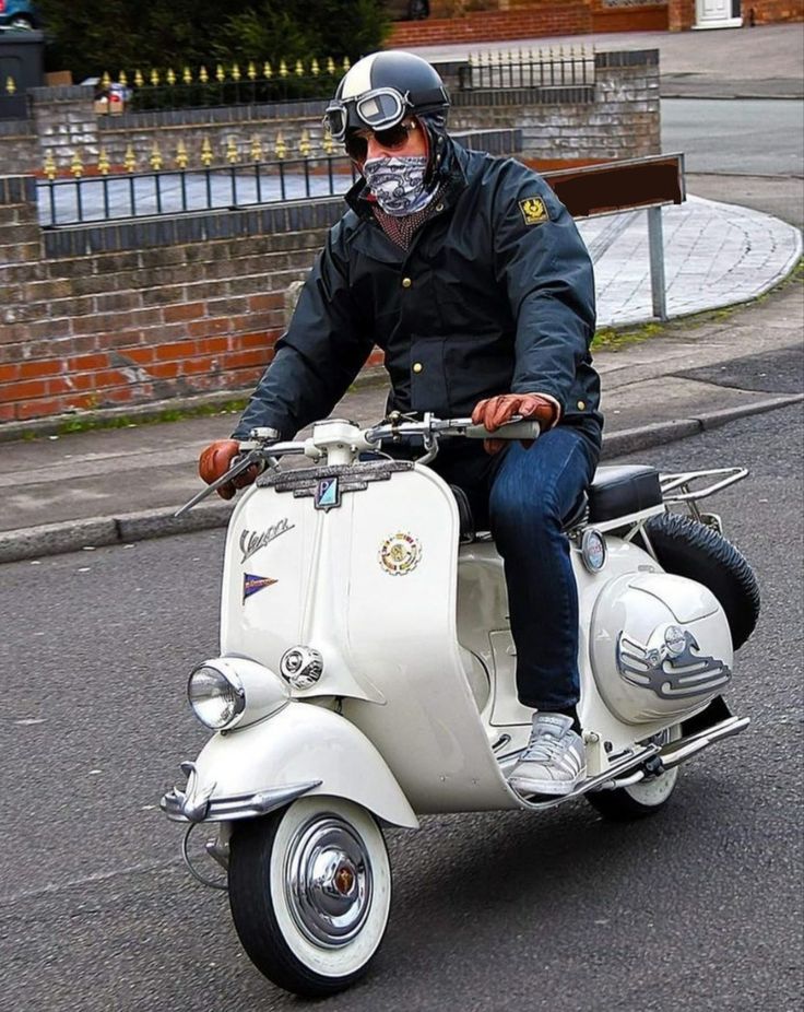 a man riding on the back of a white scooter