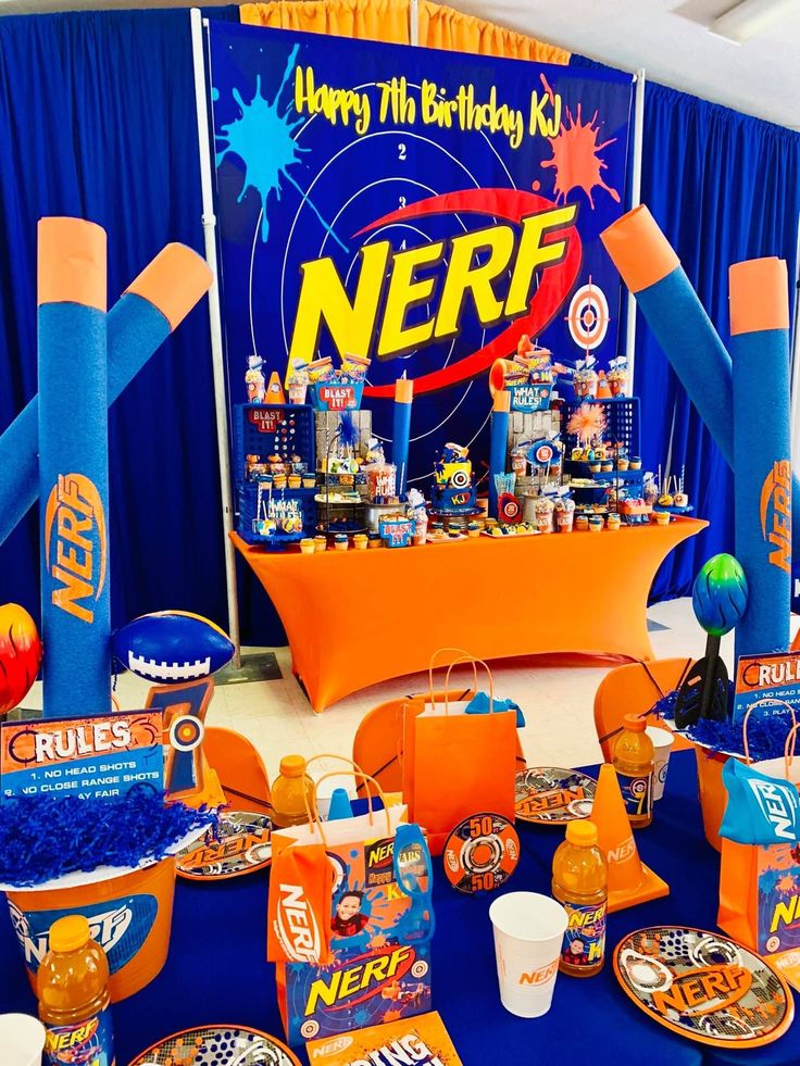 an orange and blue nerf themed birthday party with lots of food on the table