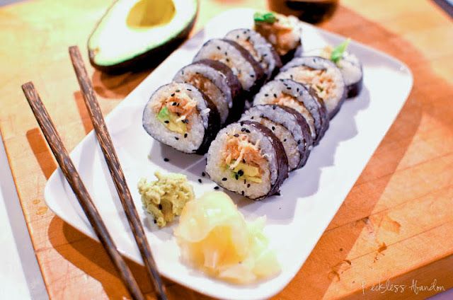 sushi on a plate with chopsticks and avocado