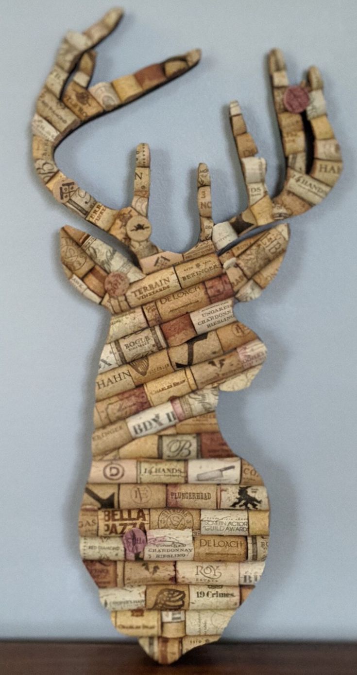 a deer made out of wine corks sitting on top of a wooden table next to a wall