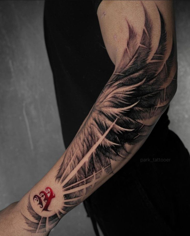 a man's arm with a feather and red heart tattoo on the left forearm