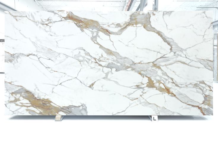 a white marble slab with gold veining on the top and bottom, sitting in a warehouse