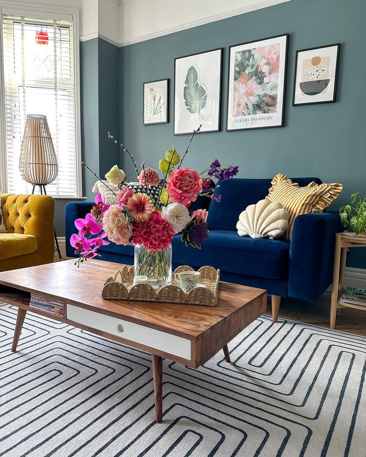 a living room filled with furniture and flowers on top of a coffee table in front of a blue couch