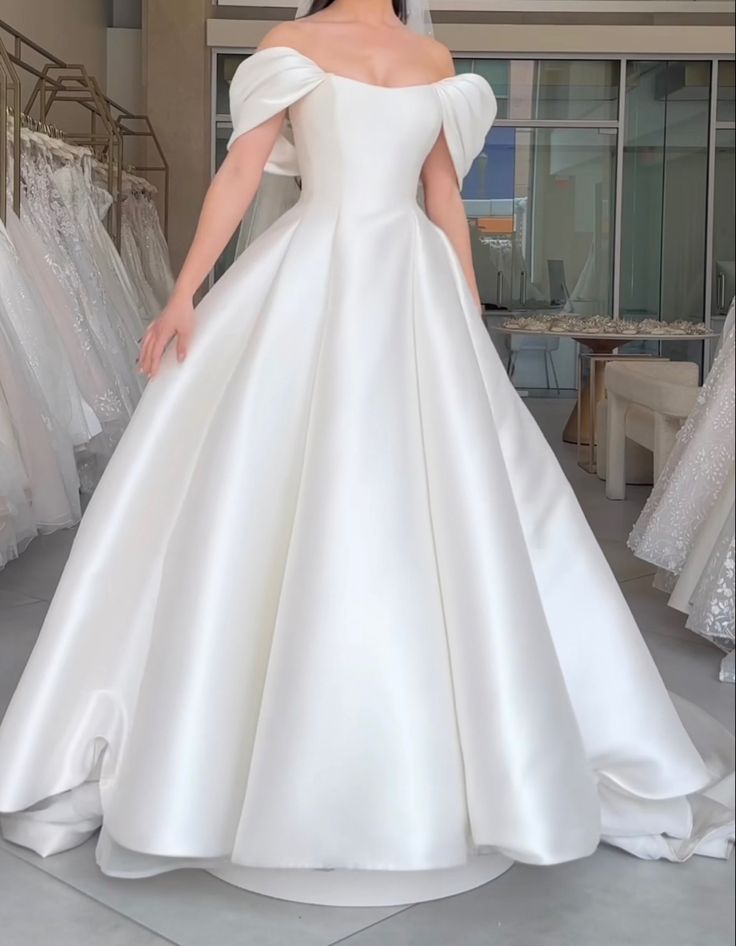 a woman in a white wedding dress standing next to some dresses