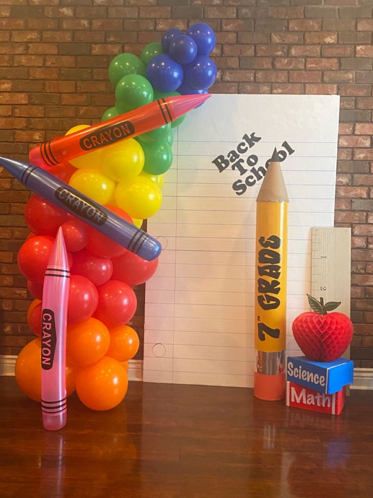 a bunch of crayons are on a table with a notepad and pencils