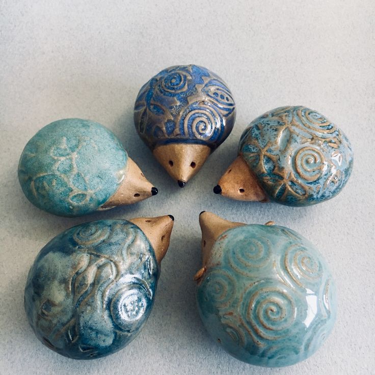 four ceramic hedges sitting next to each other on a white counter top with blue swirl designs