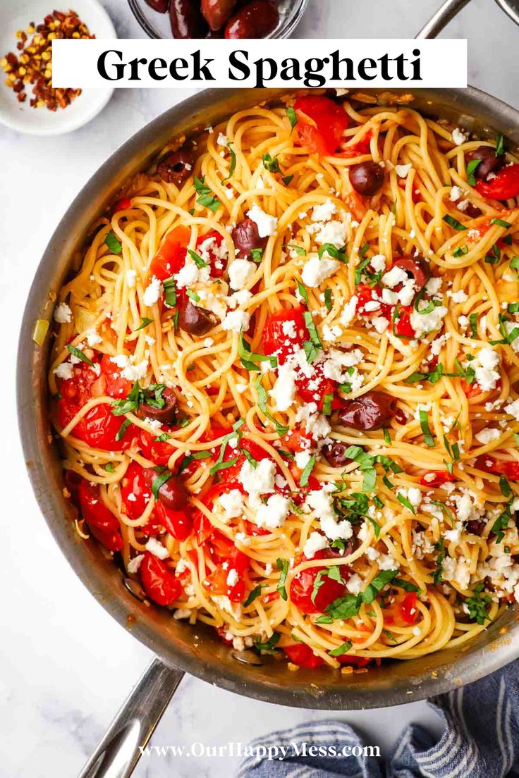 a skillet filled with spaghetti, tomatoes and feta cheese