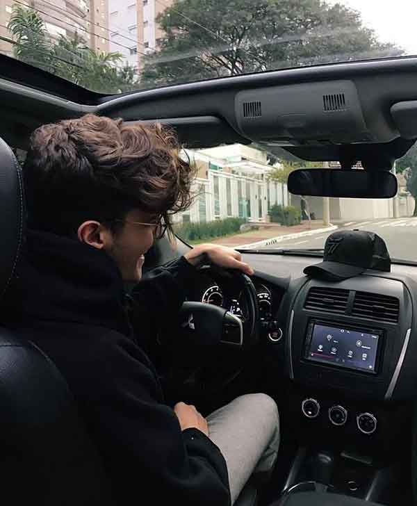 a young man sitting in the driver's seat of a car