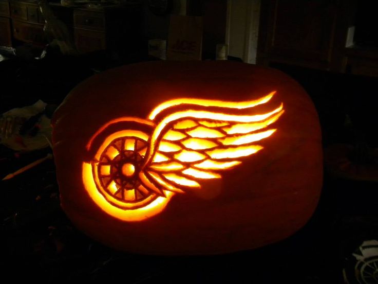 a carved pumpkin with an image of a winged wing on it's side, lit up in the dark