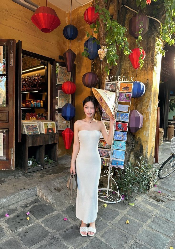 a woman standing in front of a store with red and blue lanterns hanging from the ceiling