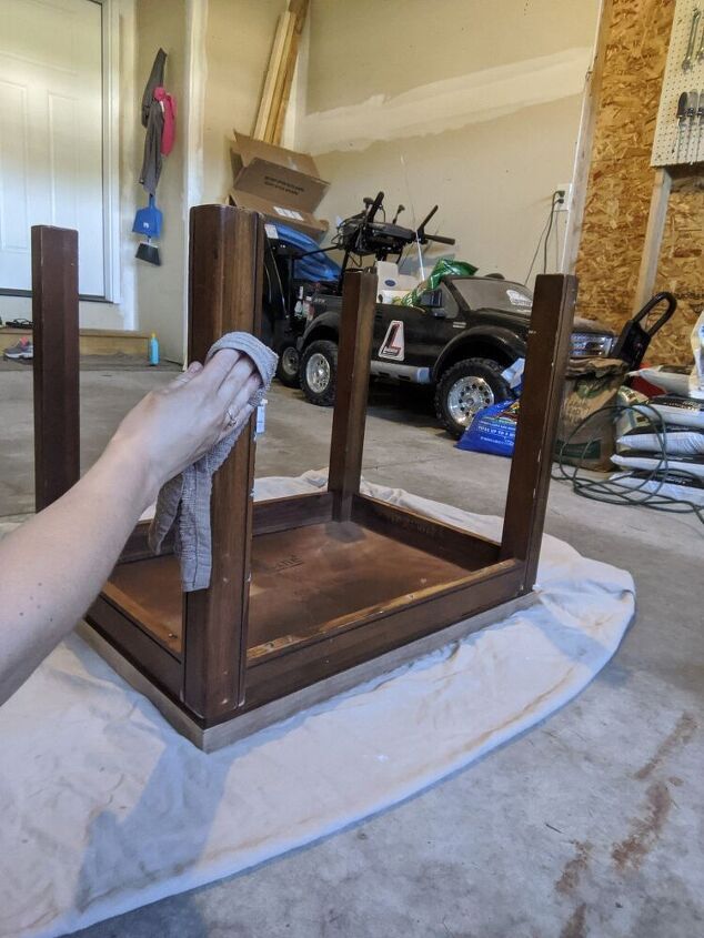 a person is cleaning the inside of a wooden cabinet with a cloth on top of it