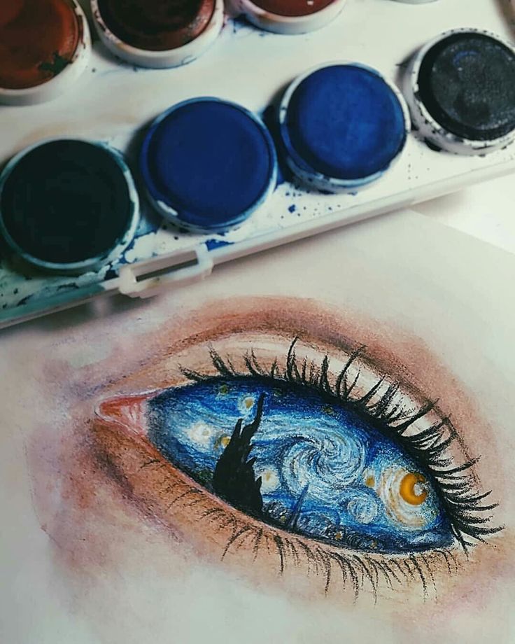 an eye is shown with paint and watercolors on the table next to it