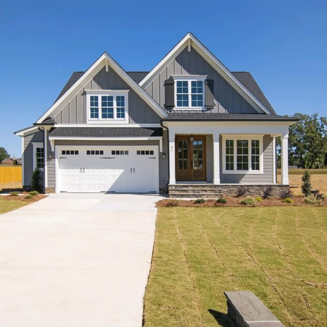 a gray house with white trim and two car garages in the front yard on a sunny day