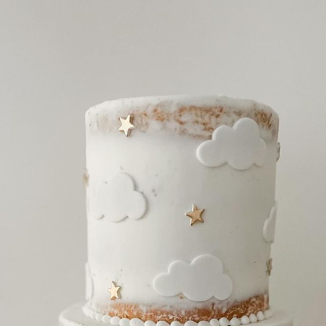 a white cake with gold stars and clouds on it