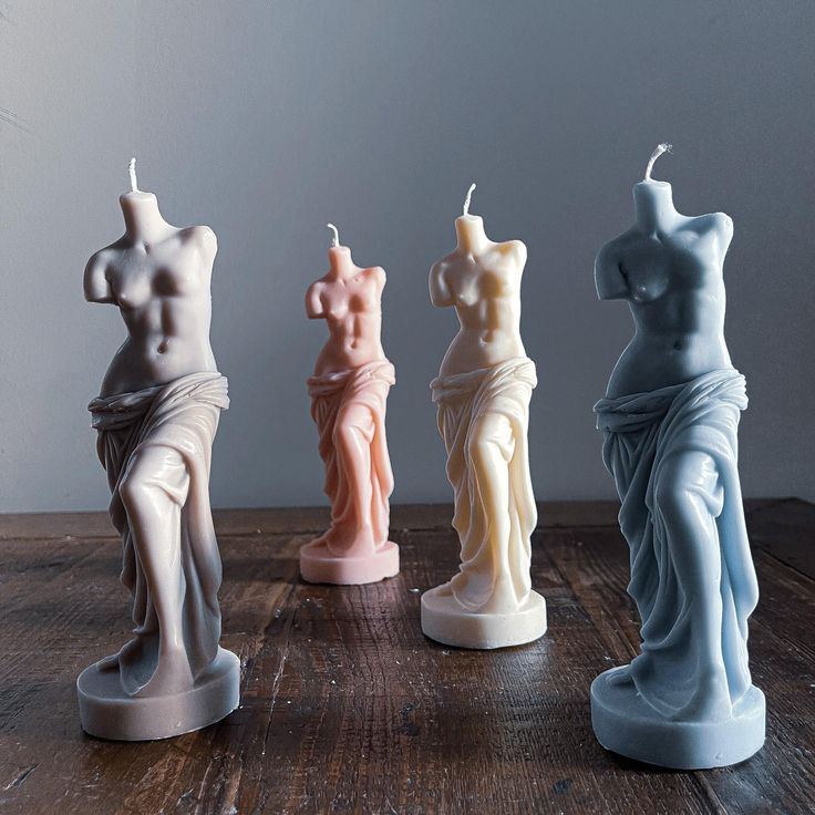 four different colored candles sitting on top of a wooden table