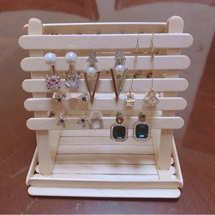 a wooden display with earrings and necklaces hanging from it's sides on a table