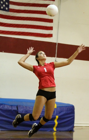 a woman jumping in the air to hit a volleyball