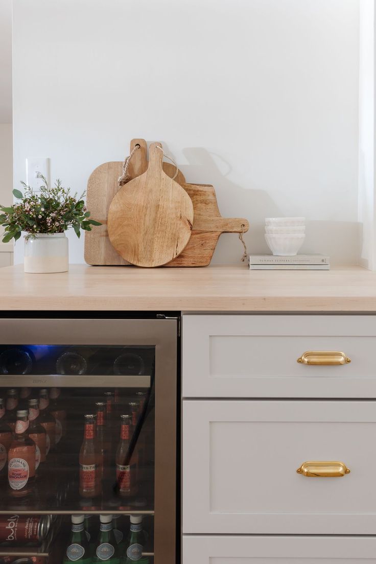 a kitchen with white cabinets and wooden cutting board on top of the counter next to an open refrigerator