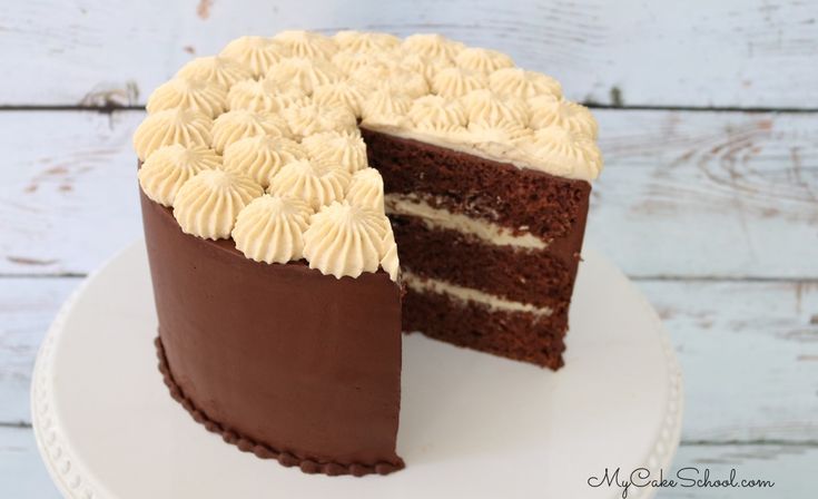 a chocolate cake with white frosting is on a plate and has one slice cut out